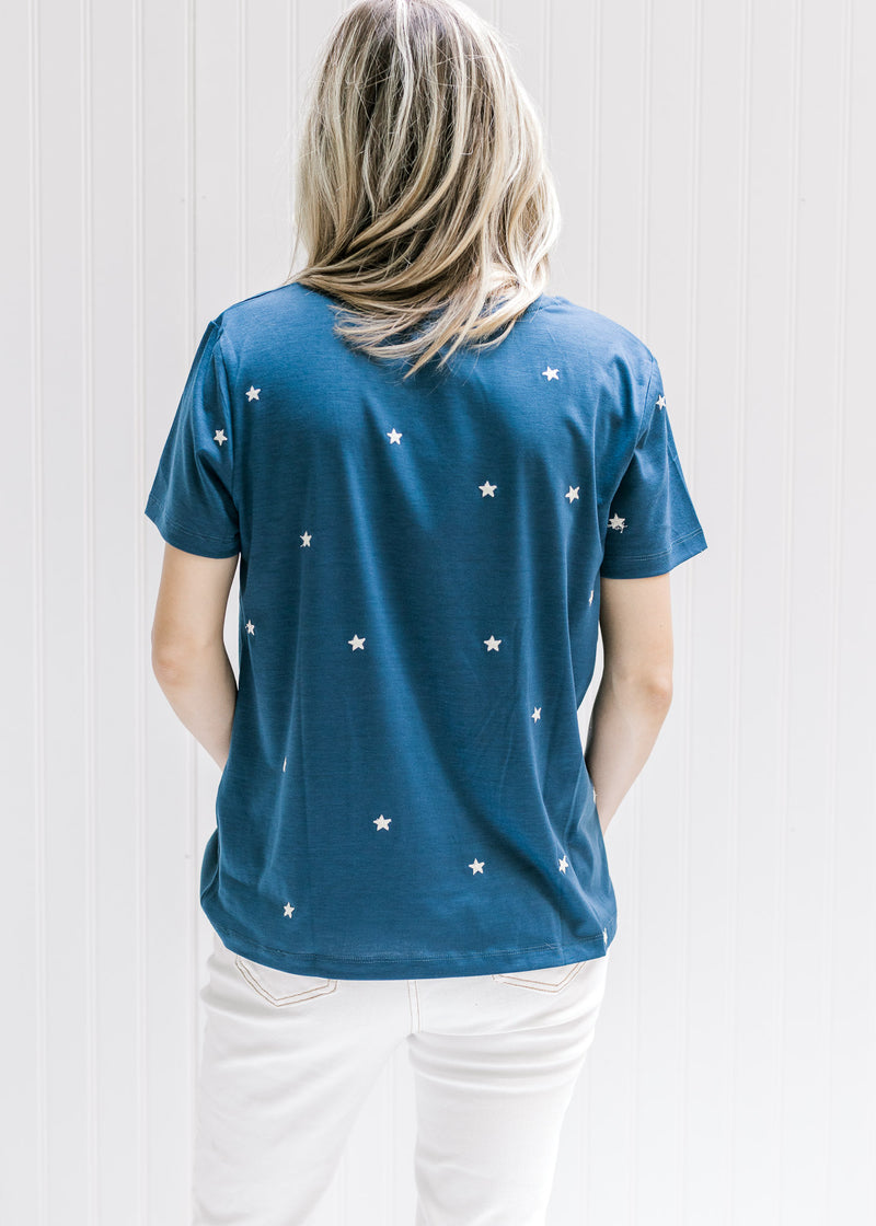 Back view of Model wearing a navy top with cream embroidered stars a round neck and short sleeves. 