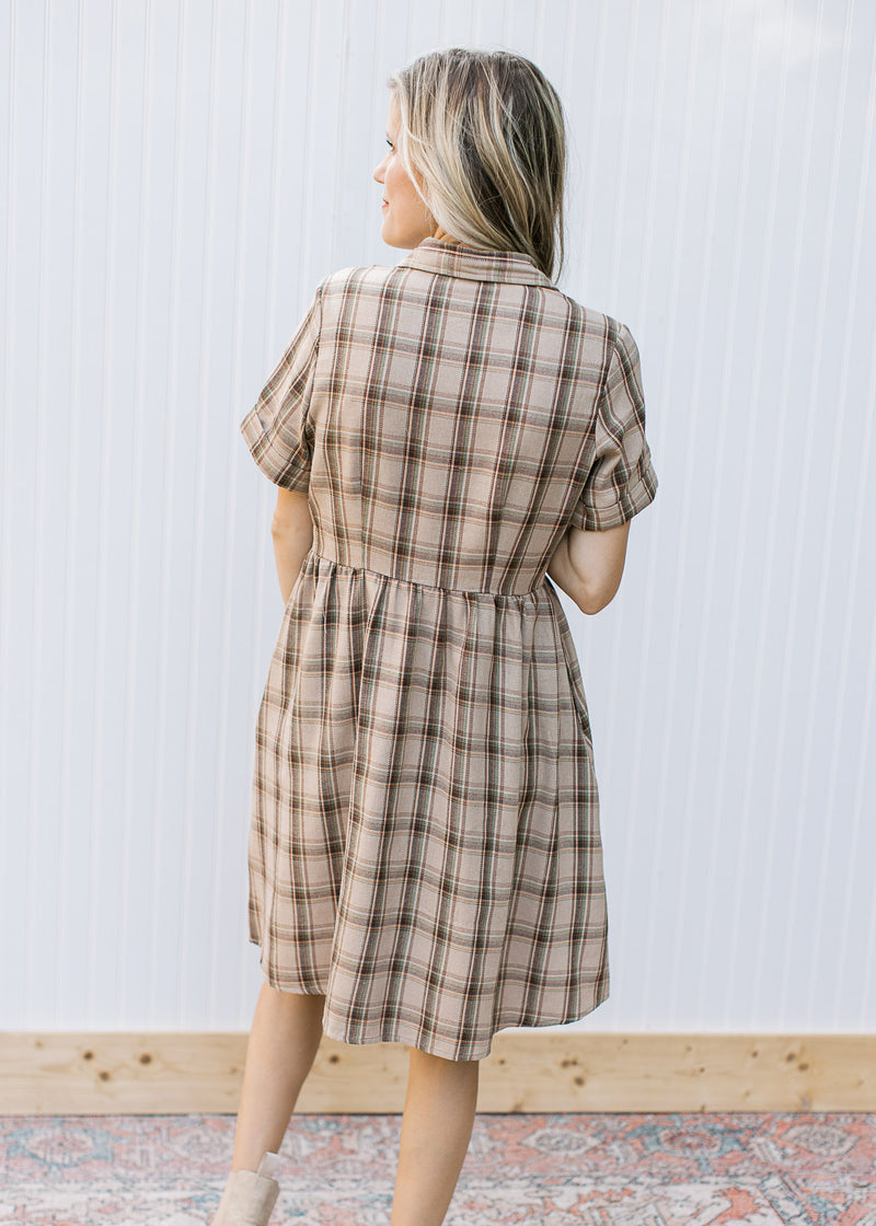 Back view of Model wearing a taupe plaid dress with button front, collar and short sleeves.