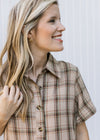 Close up of taupe dress with brown, green and orange plaid with short sleeves and button front.