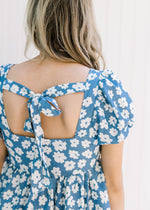 Close up view of tie closure on a blue babydoll dress with white daisies and bubble short sleeves. 