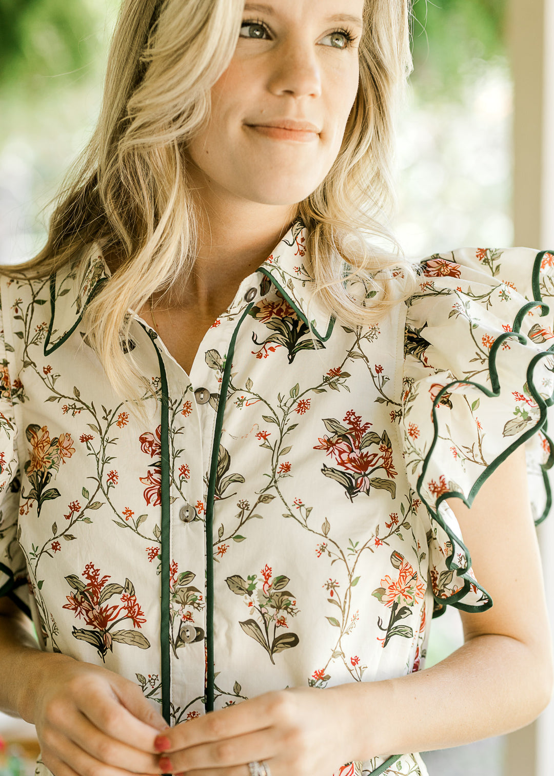 Close up of button front, collar and layered ruffle cap sleeves on a cream dress with floral. 