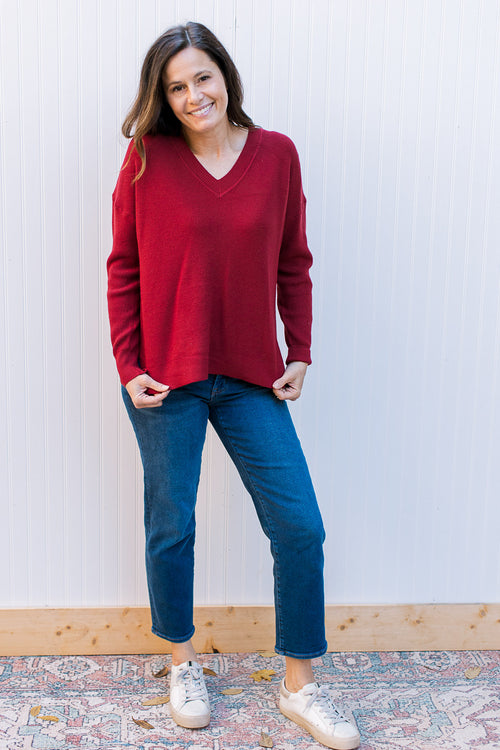 Model wearing a wine colored sweater with v-neck, long sleeves and a waffle knit material. 