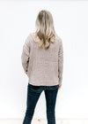 Back view of Model wearing a ribbed oatmeal sweater with a mock neckline and long sleeves. 