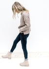 Model wearing jeans and booties with a ribbed oatmeal sweater with a mock neckline and long sleeves.