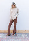 Model wearing brown pants, clogs and an oatmeal sweater with long sleeve and a mock neck.