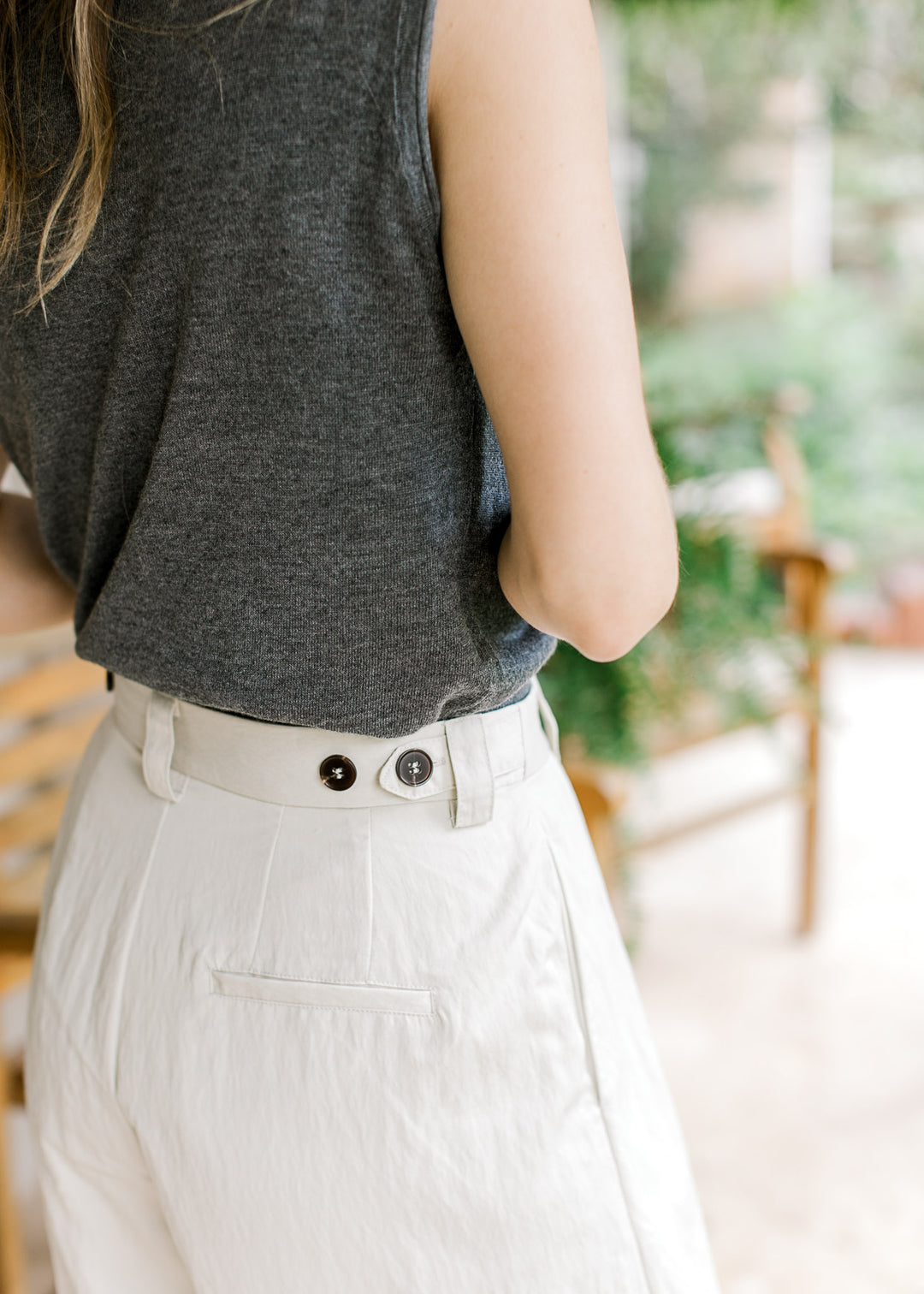 Close up of adjustable button waist and pockets on creamy white wide leg pants. 