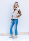Model wearing jeans, a brown top and an oatmeal puffer vest with a zip front closure and pockets.