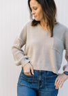 Model wearing jeans with an oatmeal v-neck sweater with crochet long sleeves and a crochet pocket.