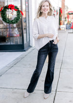 Model wearing jeans, booties and an oatmeal sweater with mother of pearl buttons.