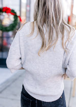 Back view of Model wearing a ribbed oatmeal sweater with an oversized fit and short sleeves.