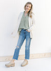 Model wearing an olive top and jeans with an off white cardigan with an open front and long sleeves.