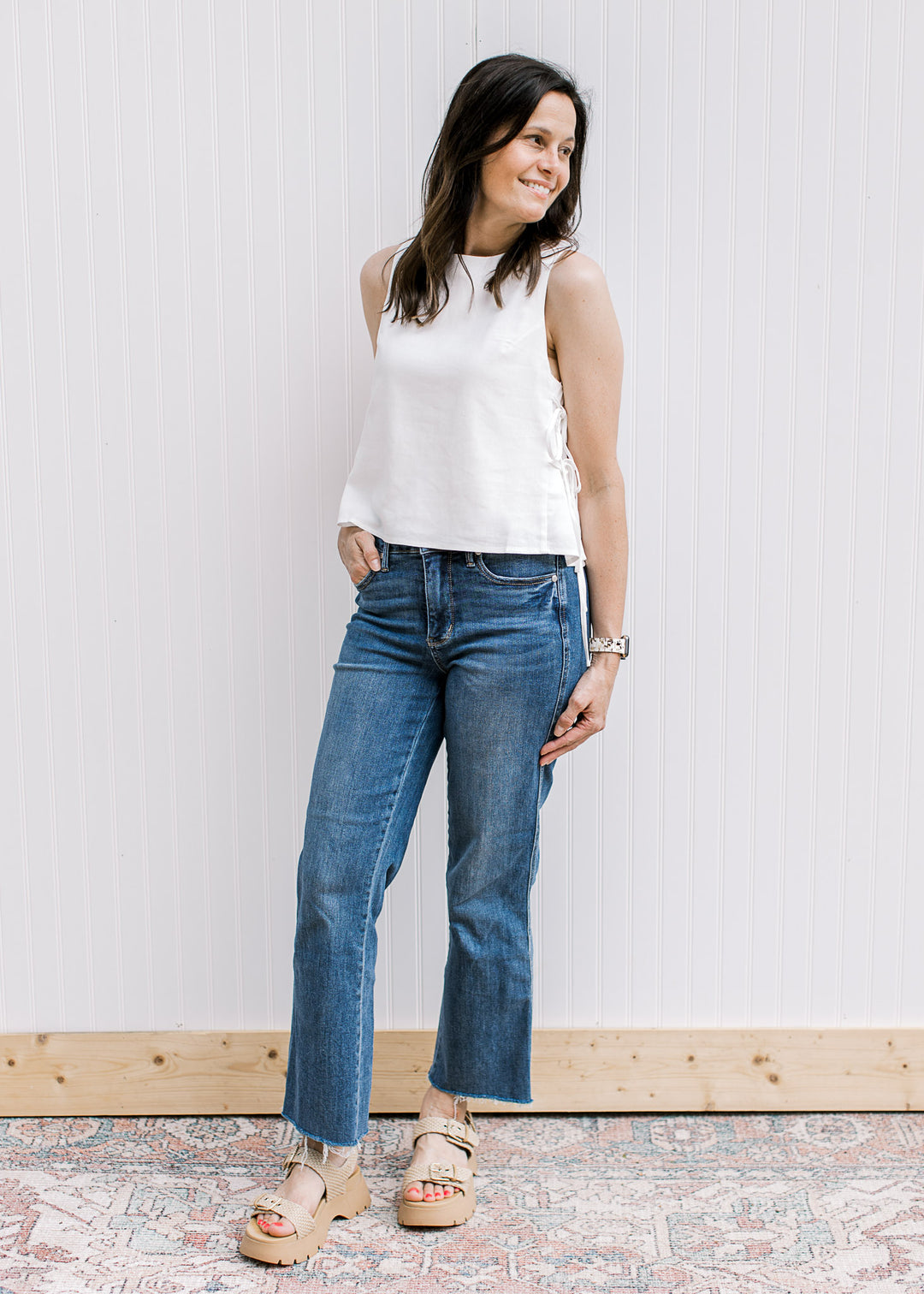 Model wearing a lined off white top with ties on both sides, a round neck and a keyhole closure. 