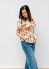 Model wearing a cream top with pink floral pattern, fully lined and flutter short sleeves.