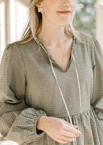 Close up of v-neck with a tie and bubble long sleeves on an olive and ivory check midi dress. 