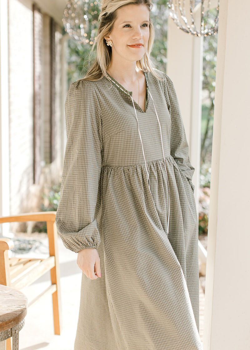 Model wearing an olive and ivory checked midi with bubble long sleeves, pockets and elastic waist.