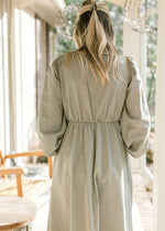 Back view of Model wearing an olive and ivory checked midi with an elastic waist band. 