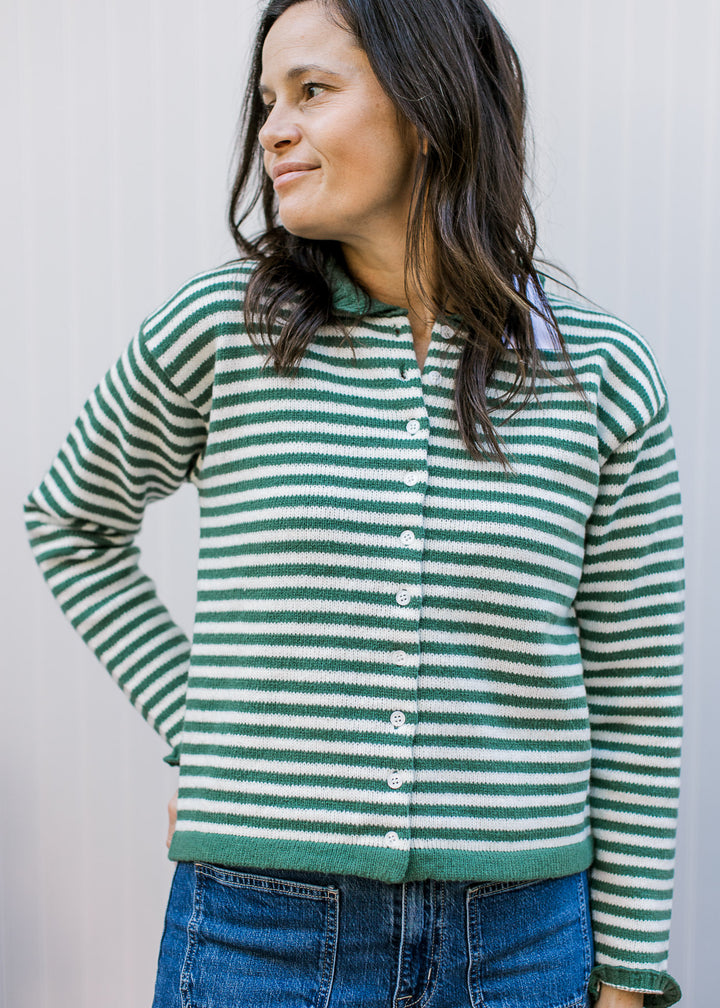 Model wearing an olive and ivory striped button up with green trim at the waist and long sleeves. 