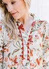 Close up of scallop detail, buttons and collar on a cream dress with olive and rust floral. 