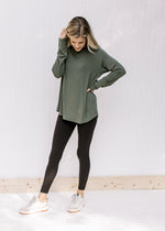Model wearing black leggings with an olive top with a round neck, long sleeves and bamboo material.
