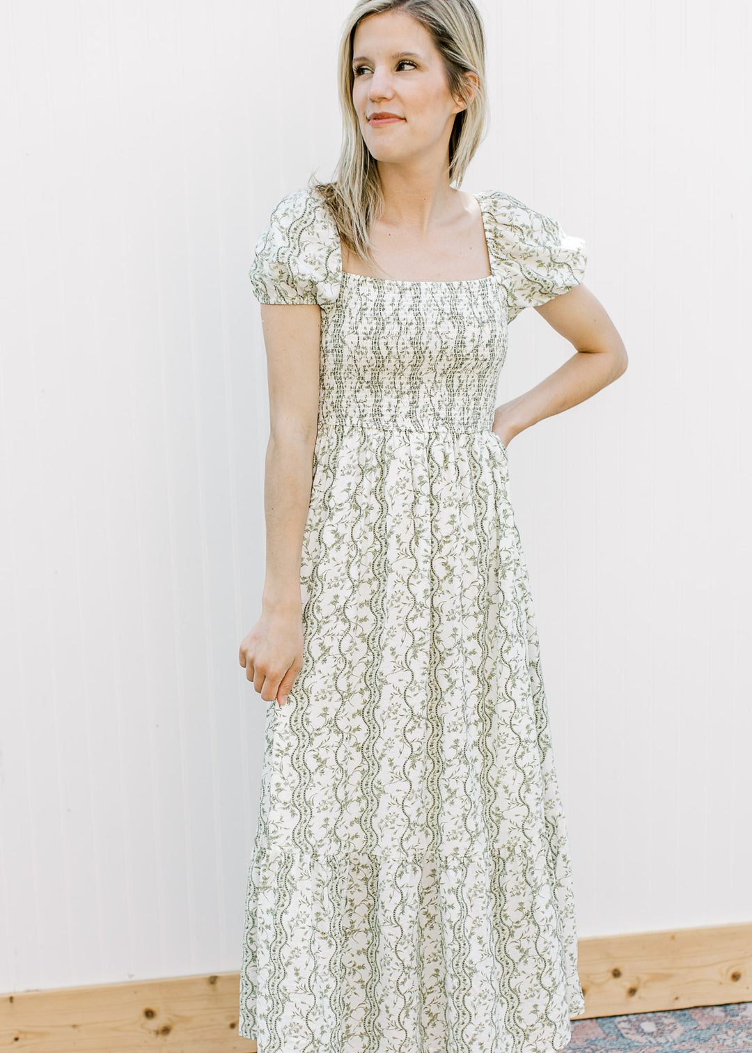 Model wearing an off-white midi with climbing olive floral, square neck and smocked bodice.