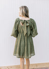 Back view of Model wearing an olive dress with a square neck with a tie and 3/4 bubble sleeves.