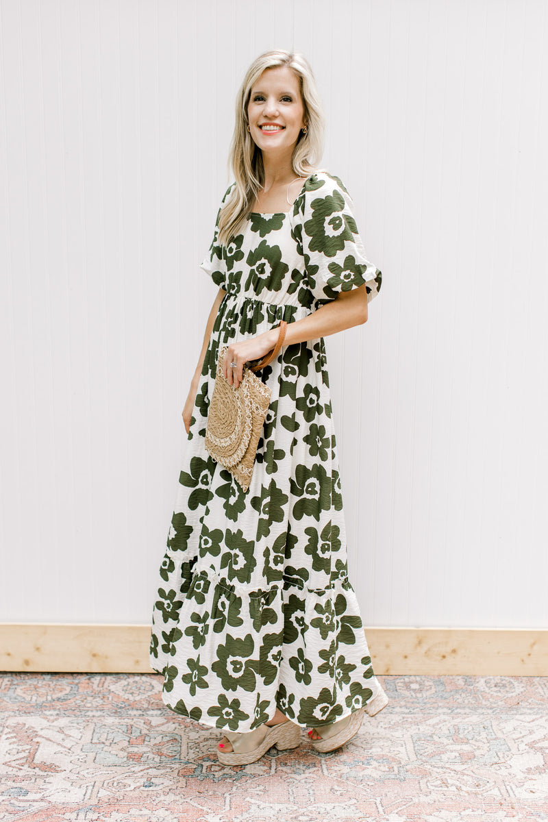 Model wearing wedges with a cream dress with olive flowers, square neck and bubble short sleeves.