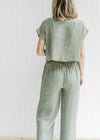 Back view of olive green set, crop top with short sleeves and wide leg bottoms with elastic waist. 