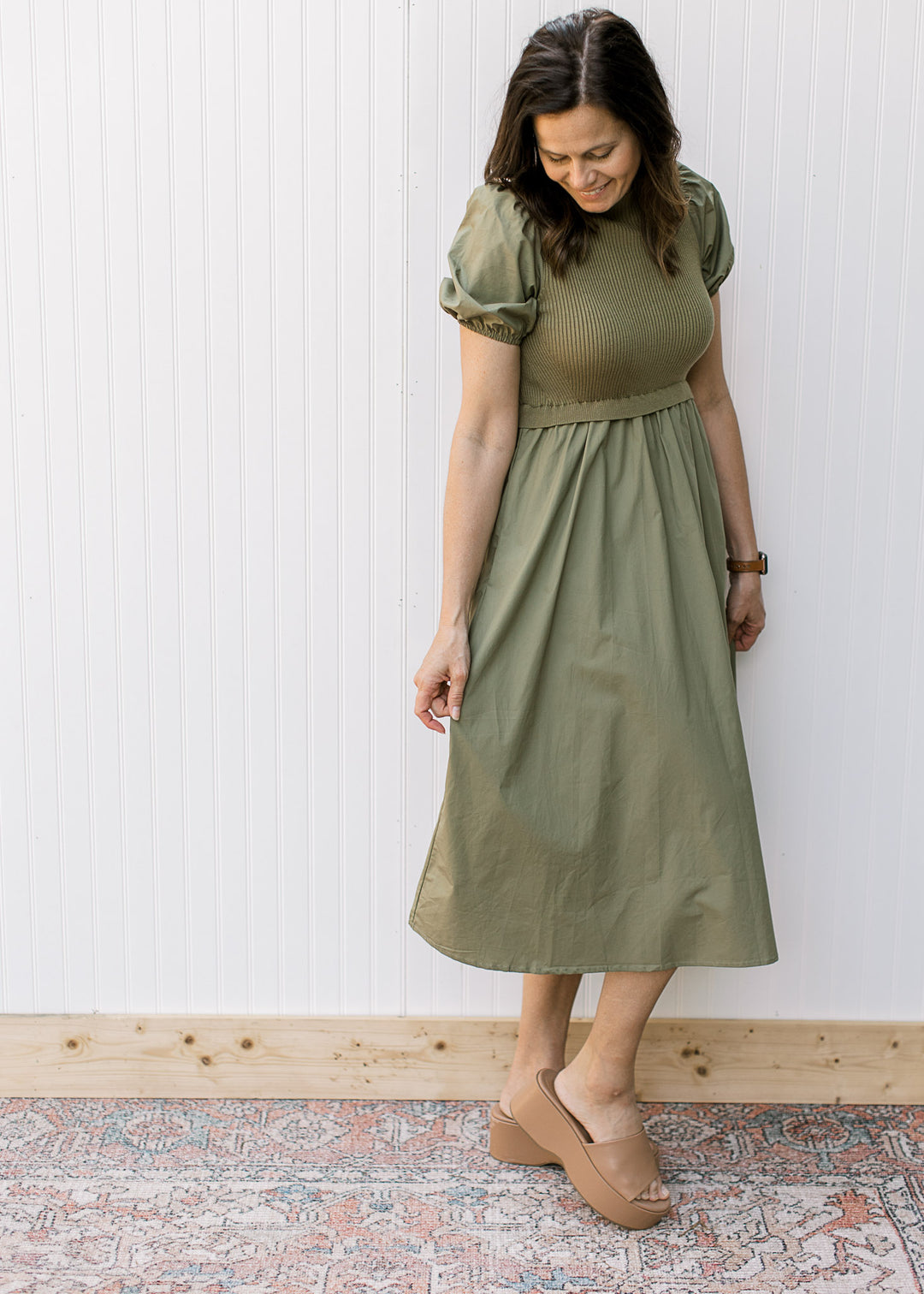 Model wearing an olive midi with a ribbed bodice, mock neck and short puff sleeves.