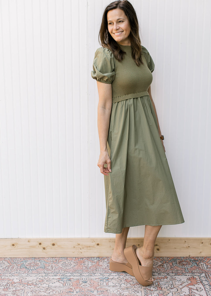 Model wearing wedges with an olive midi with a ribbed bodice and short puff sleeves.