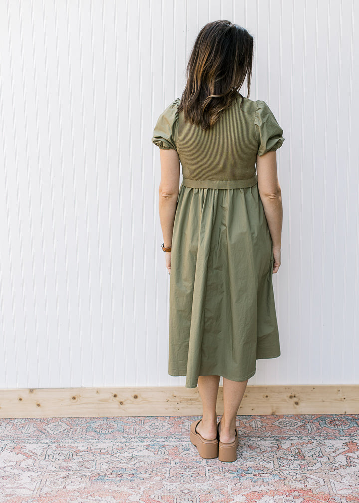 Back view of Model wearing an olive midi with a ribbed bodice, mock neck and short puff sleeves.
