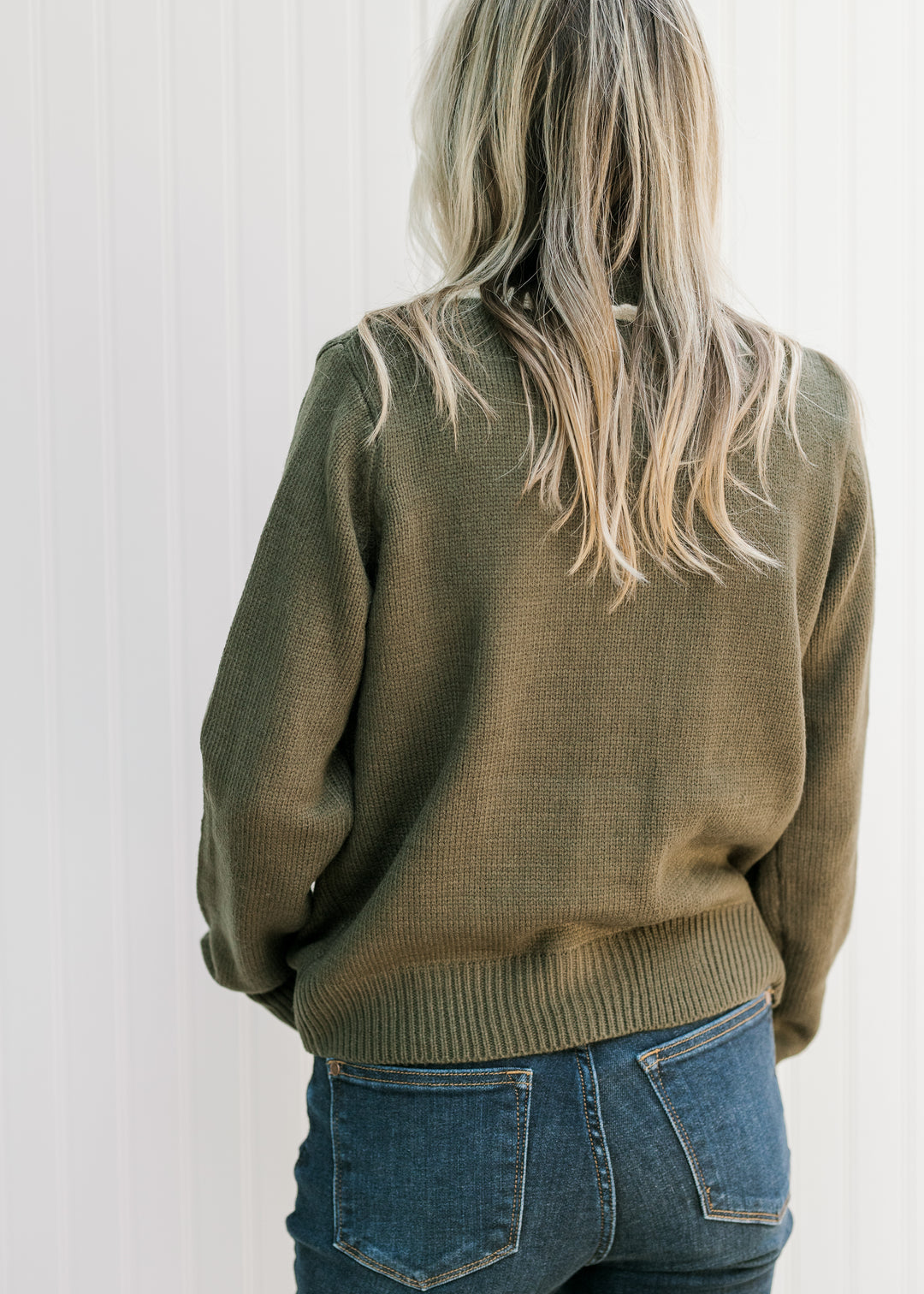 Back view of Model wearing an olive cardigan with a round neck and long sleeves. 