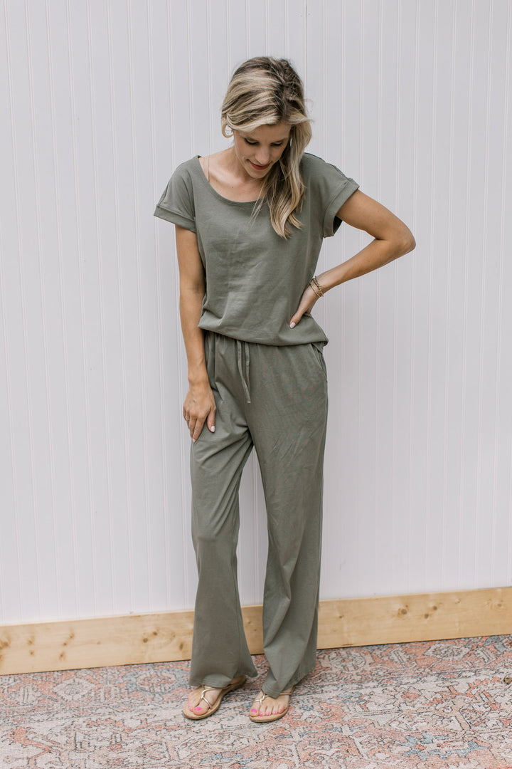 Model wearing an olive set, the top has cuff sleeves and the bottoms are wide leg with a tie. 