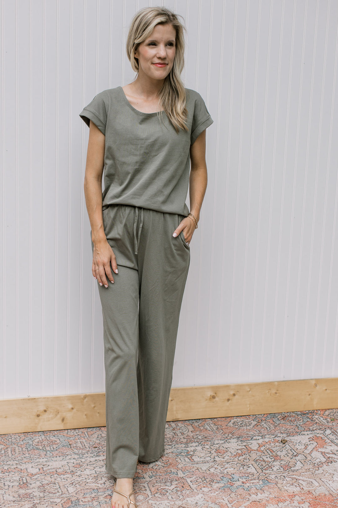 Model wearing sandals with an olive set, the top has cuff sleeves and the bottoms are wide leg.