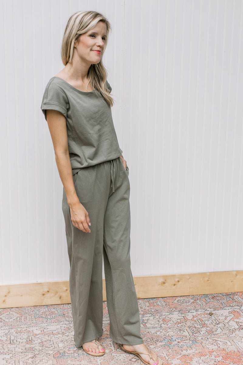 Model wearing an olive set, the top has cuff sleeves and the bottoms are wide leg with pockets.