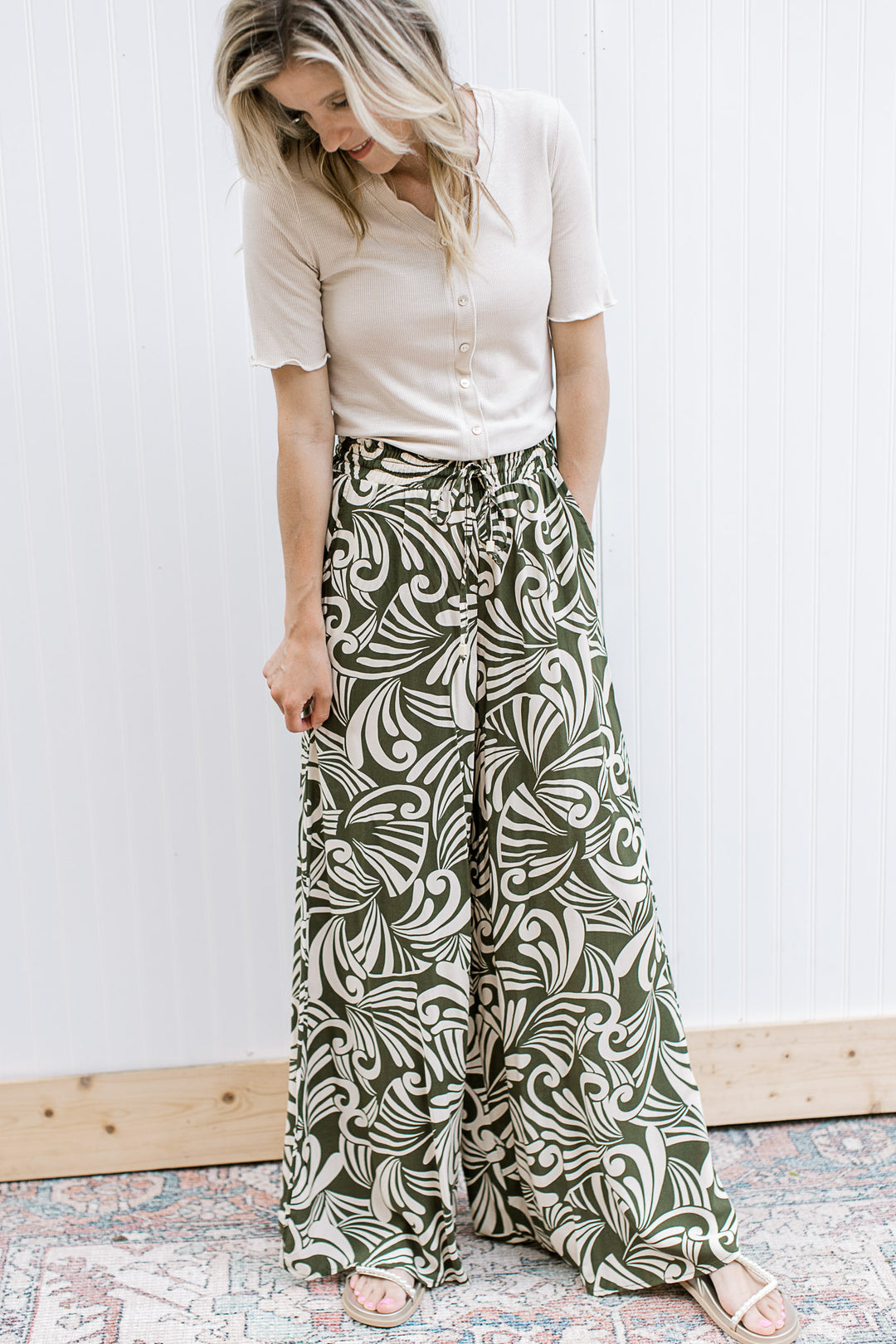 Model wearing lightweight olive and cream wide leg pants with an elastic waist and pockets. 