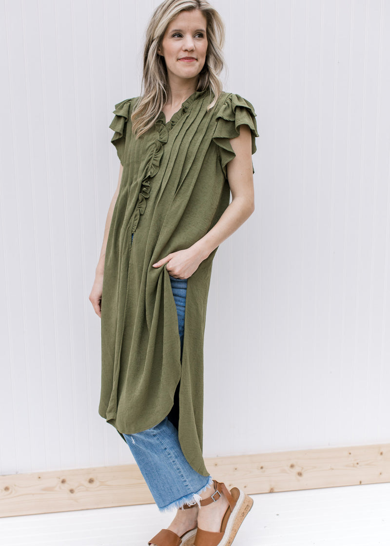 Model wearing an olive tunic with tiered ruffle short sleeves, button front and slit sides. 