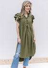 Model wearing jeans with an olive tunic with tiered ruffle short sleeves and slit sides.