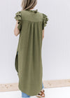 Back view of Model wearing an olive tunic with ruffle short sleeves, pleated bodice and slit sides.