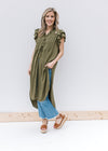 Model wearing jeans, wedge sandals and an olive tunic with ruffle short sleeves and a button front.