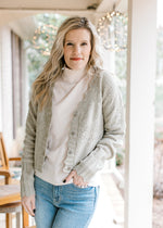 Model wearing jeans and a soft olive button up cardigan with scalloped edging, and long sleeves.