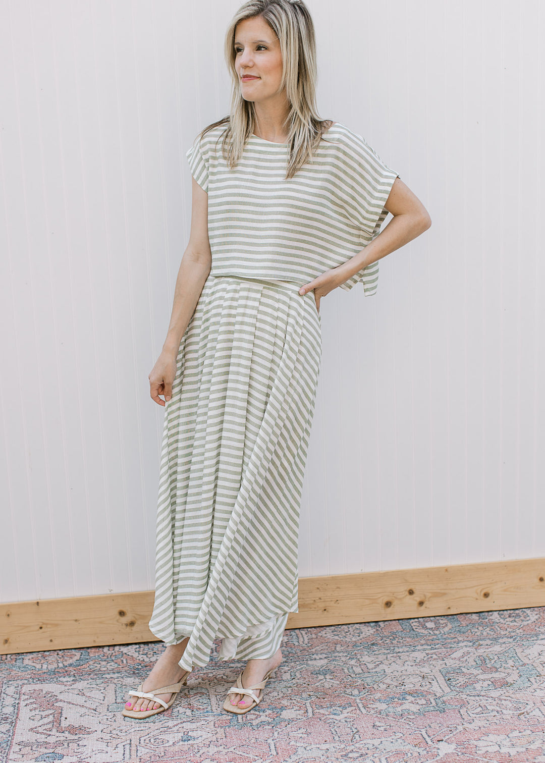 Model wearing an olive green and white stripe set with midi skirt and short sleeve top.