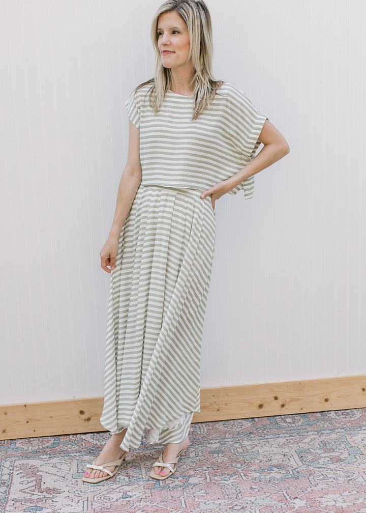 Model wearing an olive green and white stripe set with midi skirt and short sleeve top.