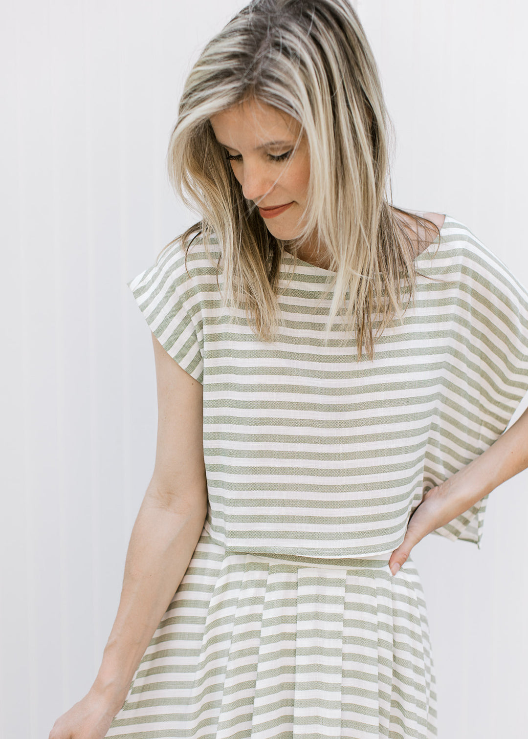 Close up of olive and cream striped top with boatneck, short sleeves and matching skirt.