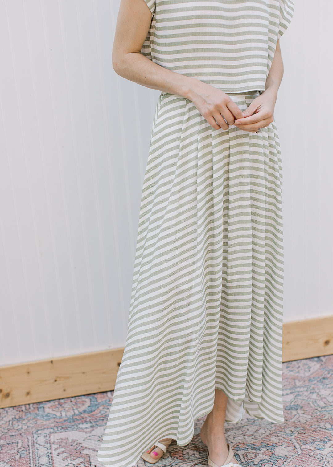 Close up of olive and cream striped midi skirt with elastic waistband, pleating and matching top.