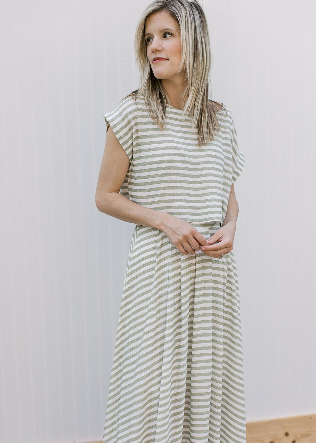 Model wearing a cream and olive striped set with short sleeves, round neck and elastic waist midi. 