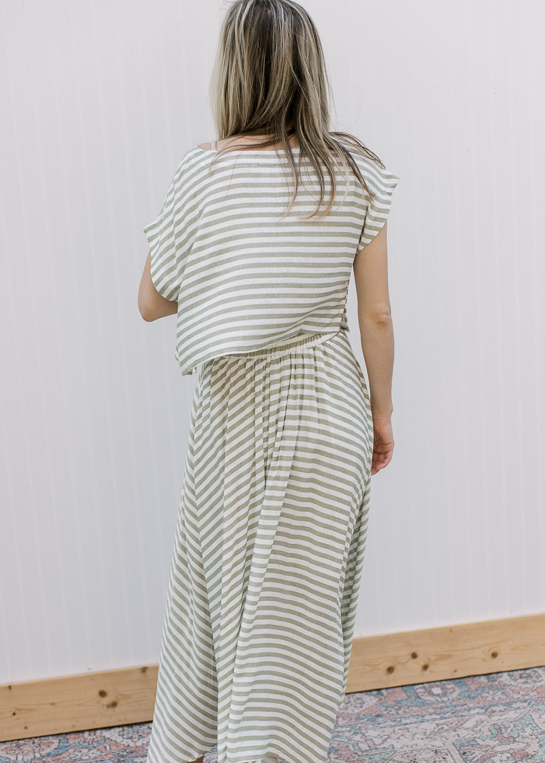 Back view of model wearing an olive green and white stripe set, with boatneck top and midi skirt.