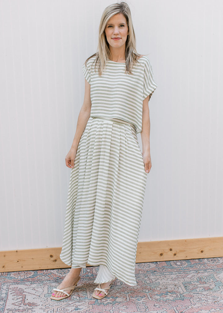Model wearing heels and an olive green and white stripe set, with short sleeve top and a midi skirt.