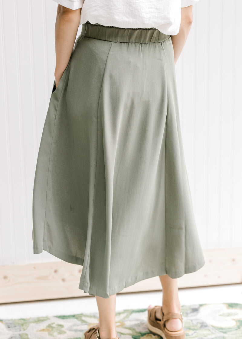 Back view of Model wearing an olive midi skirt with an elastic band and pockets