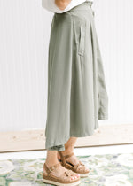 Side view of model wearing an olive midi with side slit pockets and button up closure.