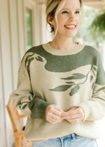 Model wearing a sage sweater with olive tree detail, long sleeves and extended shoulder.